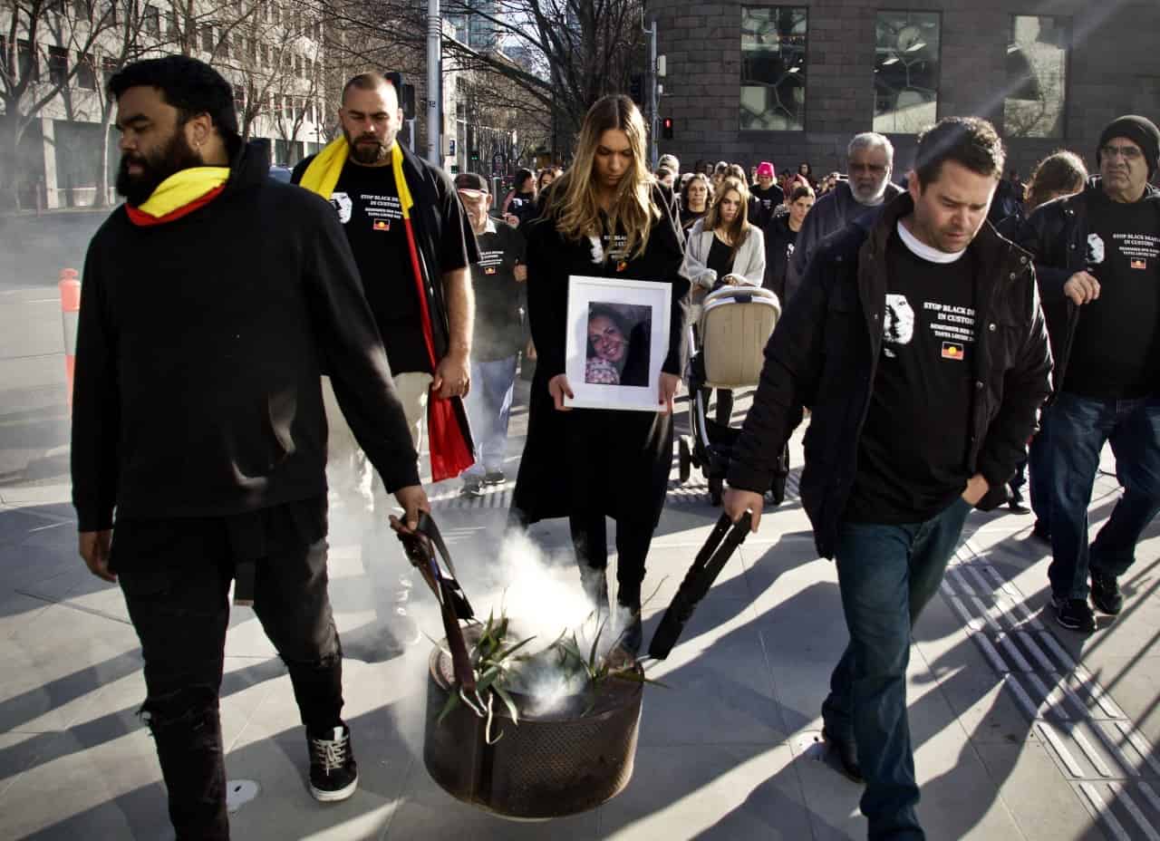 Tany Day 's Family walk down the street performing traditional smoking and walking