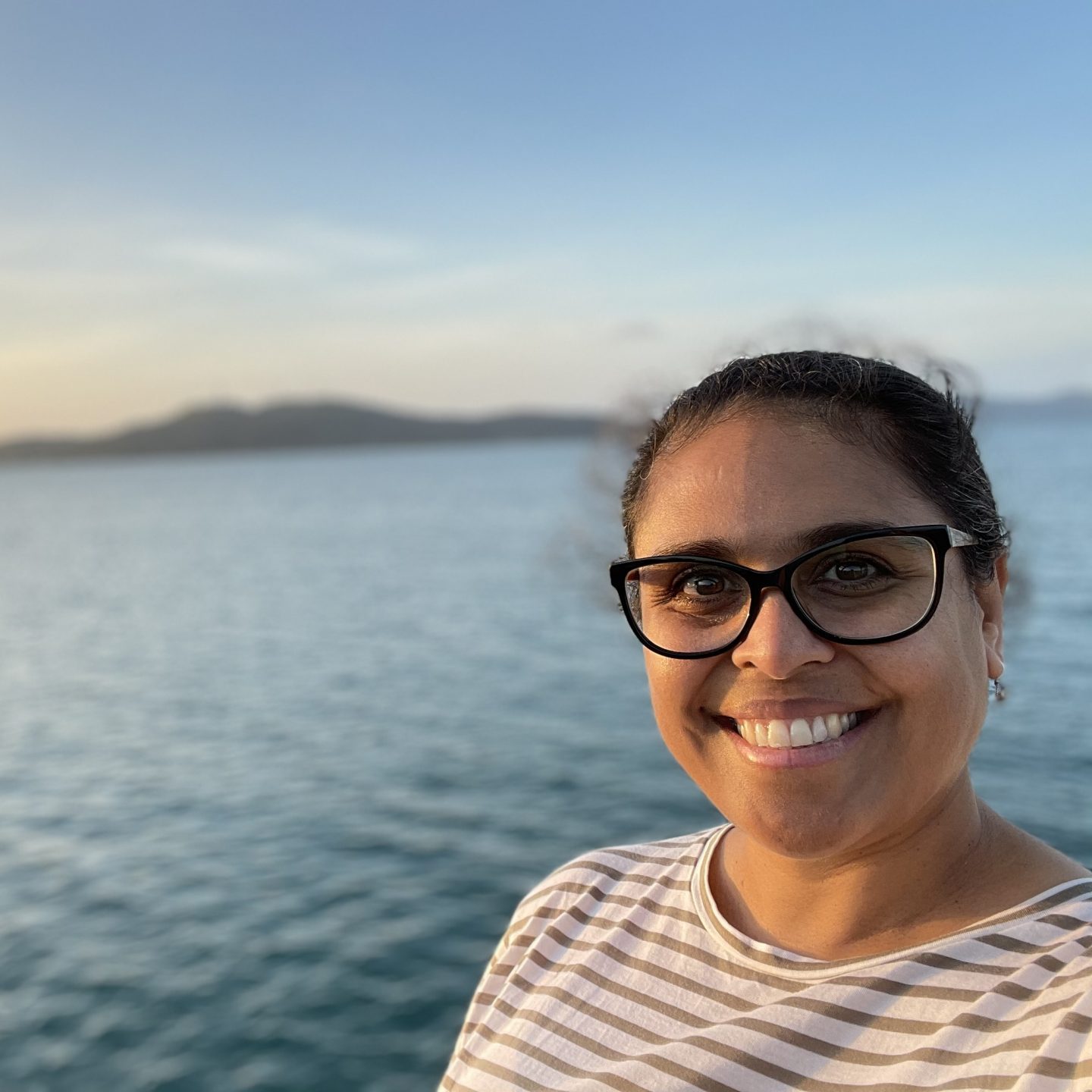Rhianna Patrick with Thursday Island in the distance behind her along with the blue waters of the Torres Strait